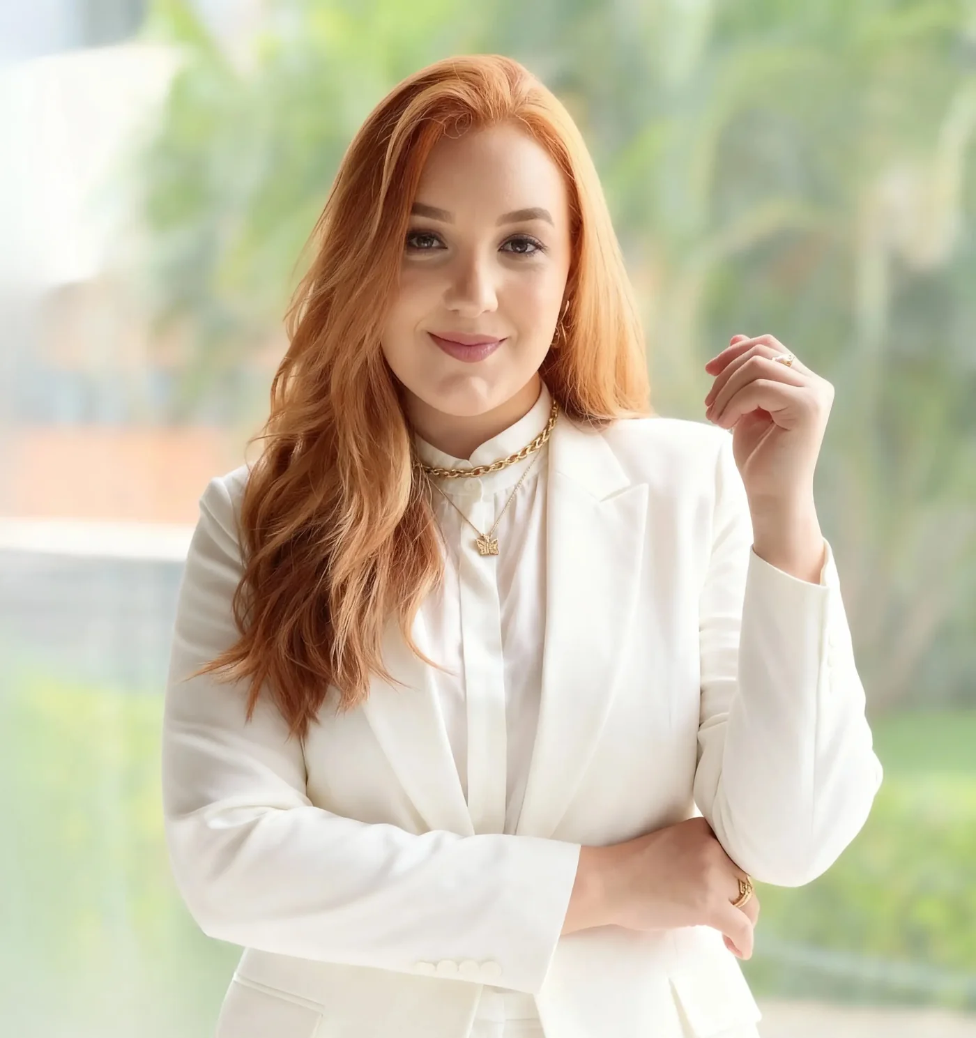 Psicóloga Thalita Macedo, de blazer branco e braços cruzados, sorrindo